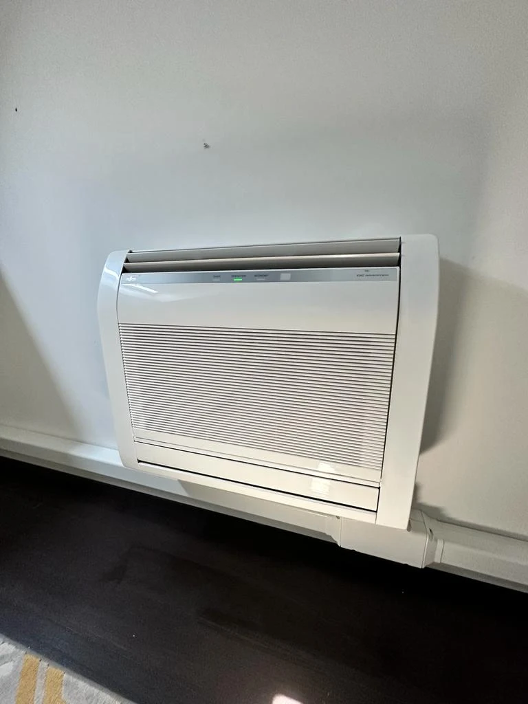 Console climatisation posée au sol dans une pièce à Bruxelles